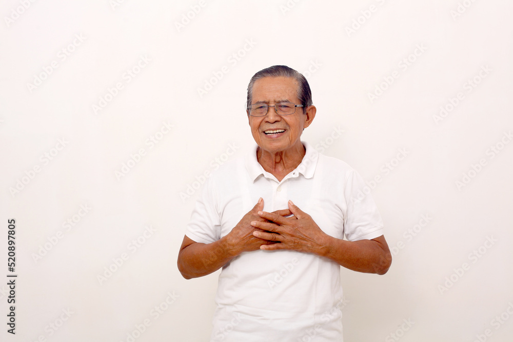 Relieved elderly asian man standing while holding his chest. Happy face ...