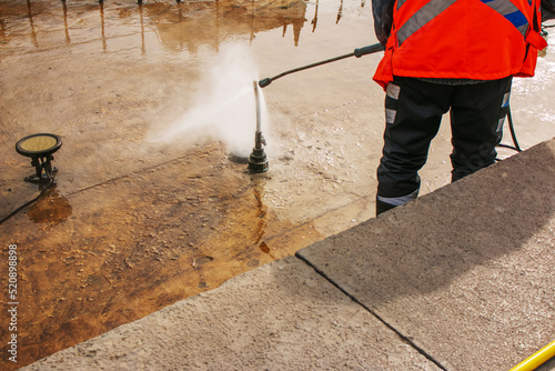 A man uses an electric pressure washer for a pressure washer. Cleaning city fountains in autumn. Workers remove the dirt that has settled during the season.
