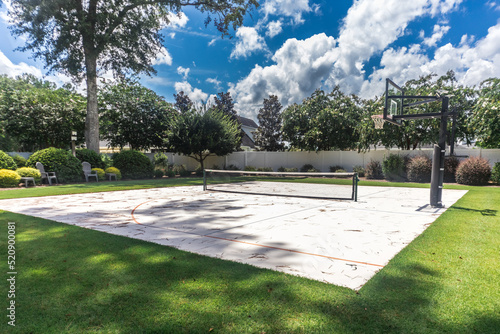 Photo A large backyard with green grass and a basketball court that has been made into