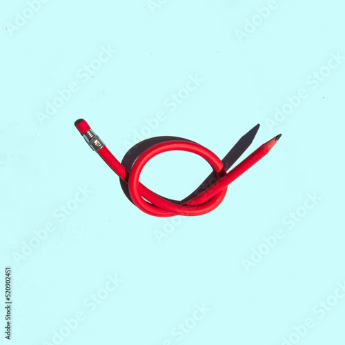 Creative inspiration block concept. Minimal composition with knotted pencil on pastel bright blue background. Minimalistic education, writing or back to school idea.