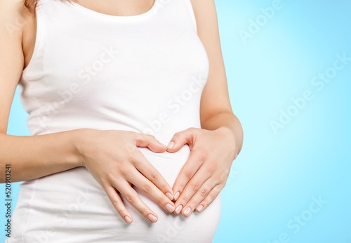 Young healthy woman hand made heart shape on her stomach. Concept of good digestive, healthy gut, probiotics, slim fit, gynecology and woman health care.