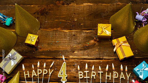 golden letters of the candle with the number happy birthday, the background of the gift boxes with candles happy birthday on the background of brown boards. Copy spacePostcard Happy birthday 4. photo