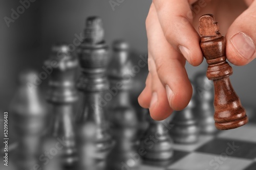 Chess player holding a piece and chess game on the chessboard, game tournament concept