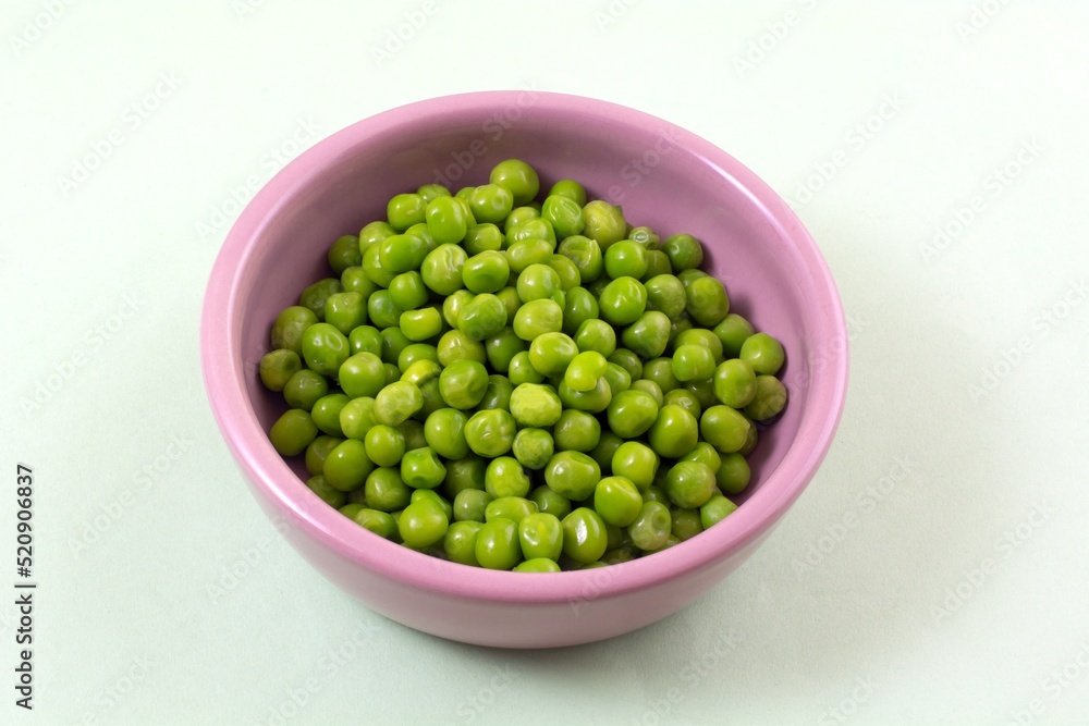 Green peas in pink ingredient bowl on light green background Green peas in pink ingredient bowl on light green background