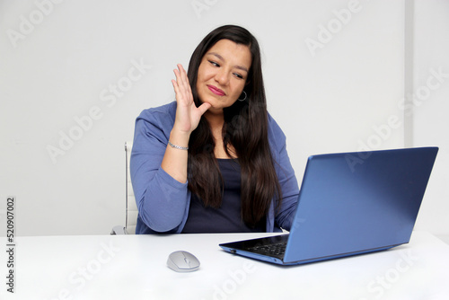 Latino adult woman speaks Mexican sign language with a deaf person through a laptop in a video call 