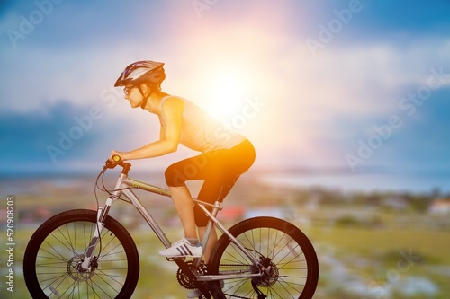 Fototapeta Naklejka Na Ścianę i Meble -  Cyclist Woman riding bike in helmets go in sports outdoors on sunny day. Fresh air. Health care, authenticity, sense of balance and calmness.