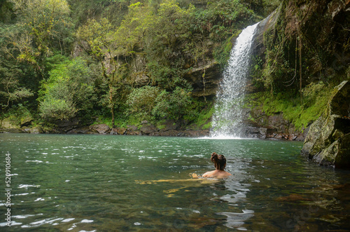 Young woman swimming at Garapia Cascade in Maquine, Rio Grande do Sul, Brazil