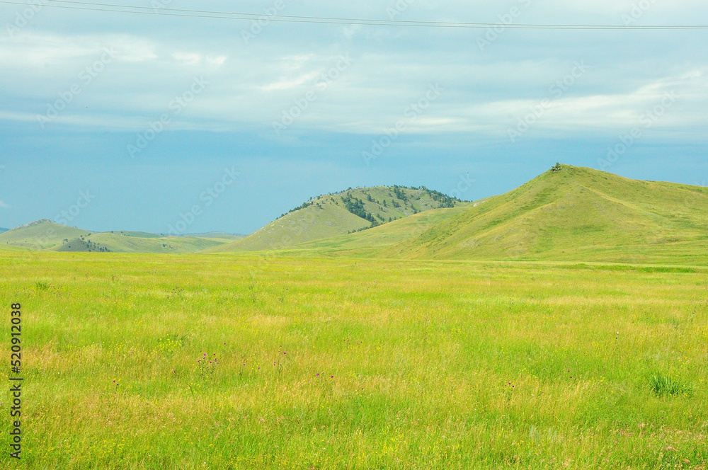 Panoramic view of the flat endless steppe and a range of high hills on the edge.