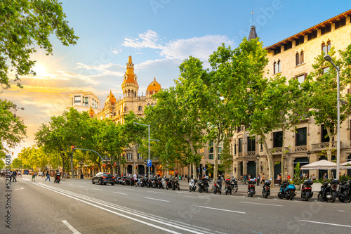 The sun sets on Paseo de Gracia avenue across from the Plaza de Catalunya in the Eixample district with the picturesque Cases Antoni Rocamora building in the sunlight in Barcelona, Spain. photo