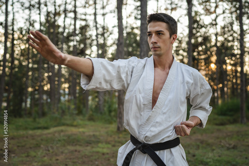 one caucasian man karateka training karate in forest in day in nature