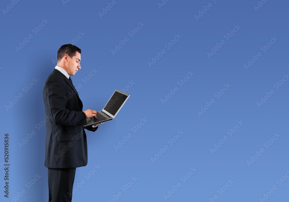 Young business man using laptop computer on blue background Young business man using laptop computer on blue background