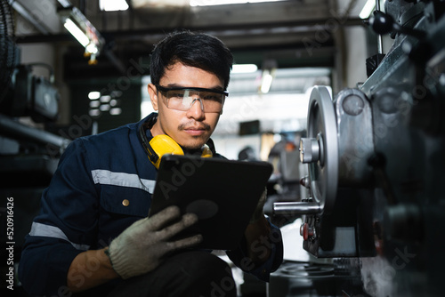 Engineer mechanical in safety suits using digital tablet working with grinding machine metal in the factory, Technician maintenance and check machinery, manufacturing steel industry. © sirichai