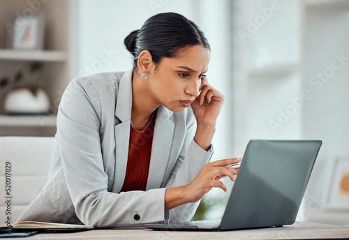 Serious, concentrating and African business woman reading an email, browsing online or looking for ideas on a laptop alone in an office at work. One black female corporate professional working