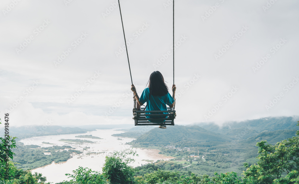 Free happy woman on a swing in the mountains