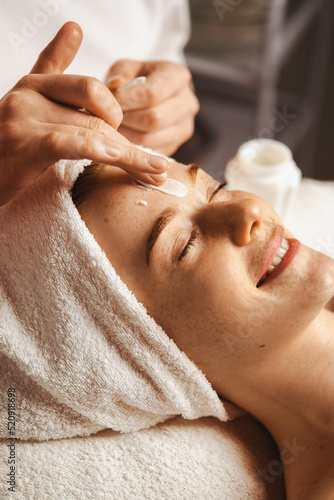 Close-up portrait of woman getting spa facial massage treatment with moisturising cream at beauty spa salon. Natural skin care cosmetic. Health care, beauty