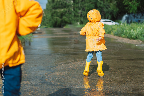 Children in yellow rubber boots walk through puddles.