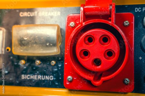 Power outlet with red grounding on the body of a gasoline electric generator close-up