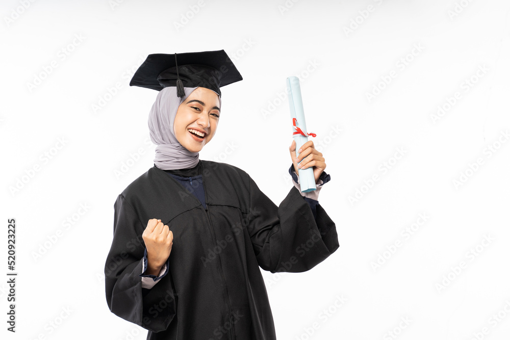 Excited female graduate student in black toga holding certificate roll on isolated background Excited female graduate student in black toga holding certificate roll on isolated background