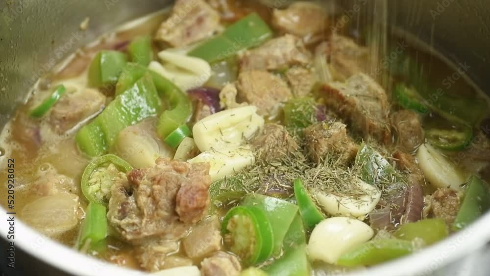 The cook sprinkles dried thyme on the braised pork with green peppers and onion while the food is cooking in the saucepan.
The cook sprinkles dried thyme on the braised pork with green peppers and onion while the food is cooking in the saucepan.