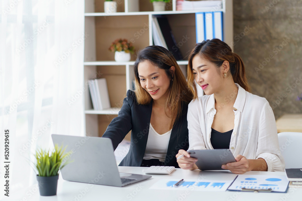 Two young Asian businessmen discuss working on investment project and planning strategies by using a laptop computer in the office. Two young Asian businessmen discuss working on investment project and planning strategies by using a laptop computer in the office.