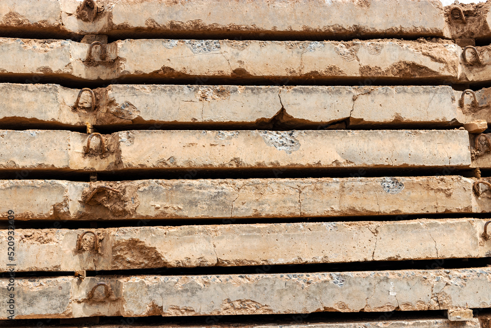 Old reinforced concrete road slabs stacked on a construction site for later use. Temporary road surface. Old reinforced concrete road slabs stacked on a construction site for later use. Temporary road surface.
