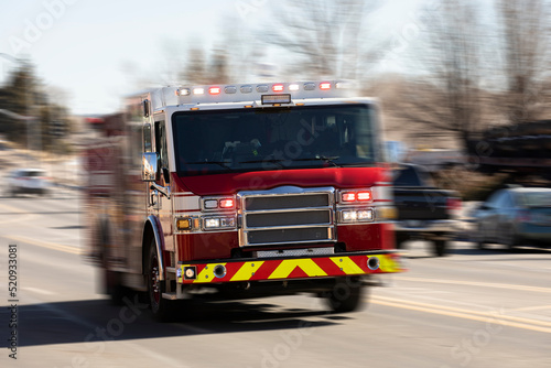 Motion panned view of a fire truck racing with sirens blaring to the scene of an emergency.