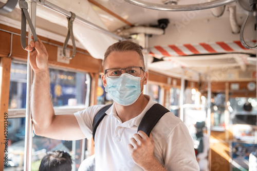 Caucasian man student on face medical mask while traveling inside public transport, tram Turkey