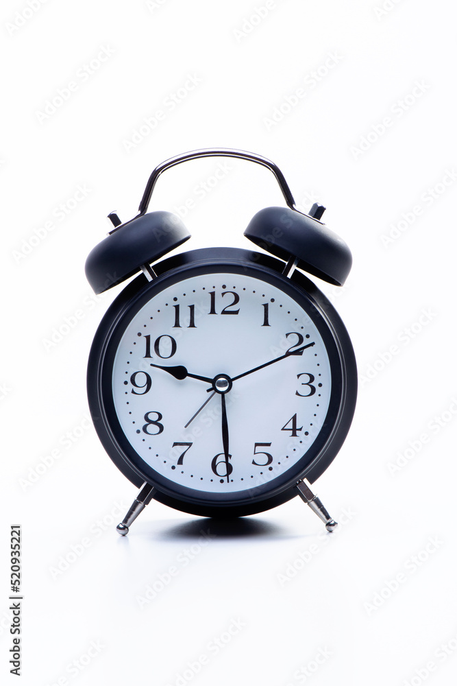 Black round metallic retro alarm clock isolated on white background. The clock shows daytime working hours Black round metallic retro alarm clock isolated on white background. The clock shows daytime working hours