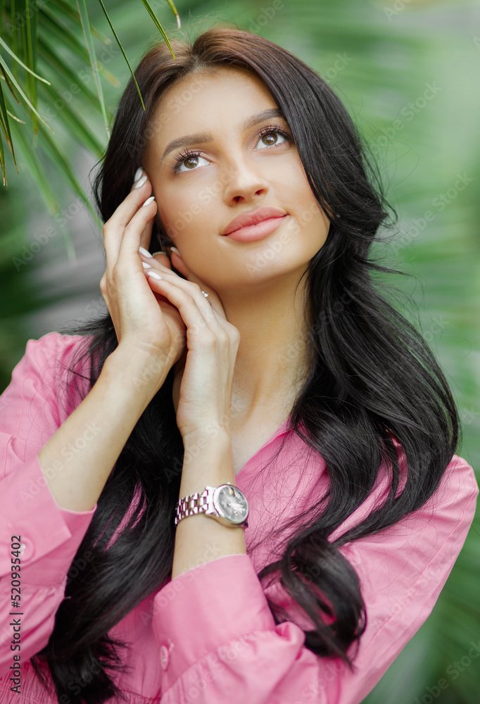 Dreamy woman with long wavy brunette hair posing in tropical botanic garden with greenery on the background. Dreamy woman with long wavy brunette hair posing in tropical botanic garden with greenery on the background.