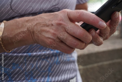 Schlanke Frauenhände von stehender Frau halten Handy