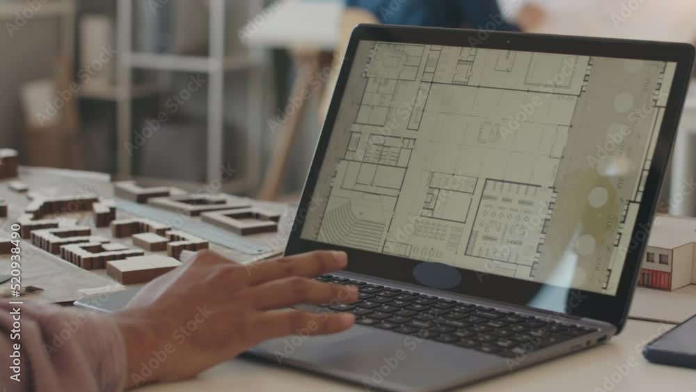 Slowmo closeup of unrecognizable male architect creating house plan on laptop while working in office Slowmo closeup of unrecognizable male architect creating house plan on laptop while working in office