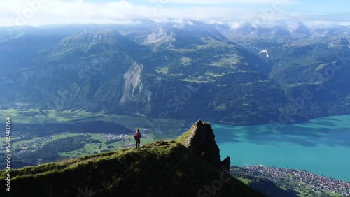 A man in the mountains standing on a cliff with a view over Lake Brienz very close to Brienzer Rothorn on a clear morning. Ready for an outdoor adventure in the nature of the Alps of Switzerland photo