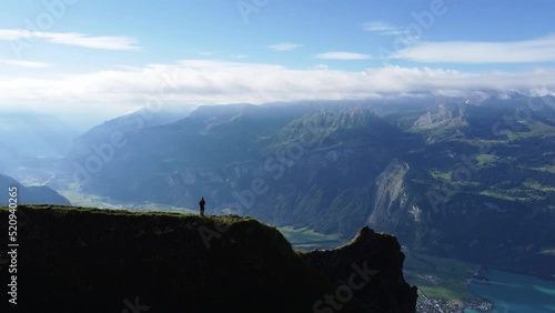 A man are standing alone on dramatic ridge line in the mountains of Switzerland, hiking with a view over Lake Brienz near Brienzer Rothorn photo