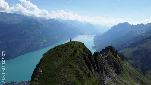 Aerial rotation drone shot of the scenery of the Alps of Switzerland on a clear blue day, overlooking Lake Brienz and the mountains in the background and some dramatic rock formation in the foreground photo