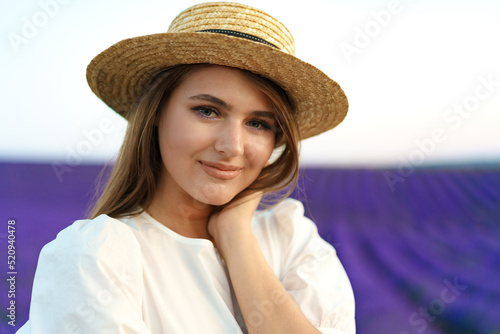 Young woman in a straw hat walking in a lavender field © fotofabrika
