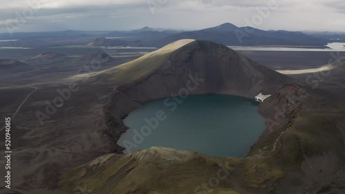 Drone flight over beautiful Crater lake surrounded by black sand desert on Iceland Island during grey dark day photo