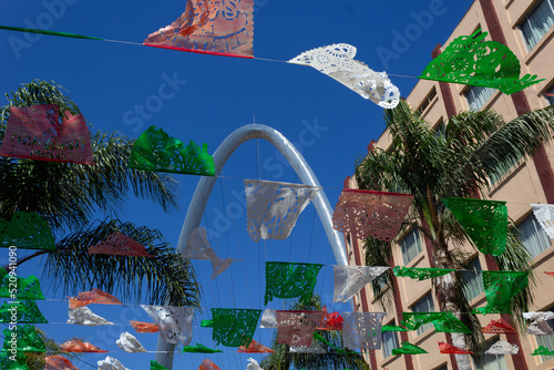 low view of tijuana mexico street with colorful party decorations with view to the arch