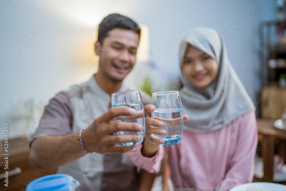 muslim couple wake up early to have sahur or suhur breakfast for fasting. clock at foreground showing the time muslim couple wake up early to have sahur or suhur breakfast for fasting. clock at foreground showing the time