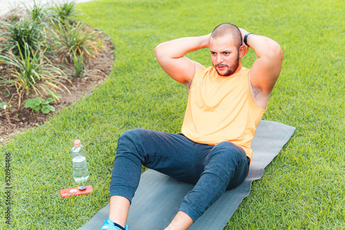 Young latin guy exercising on the ground in the park