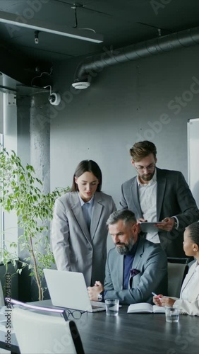 A group of people are discussing a project, having gathered around open laptop