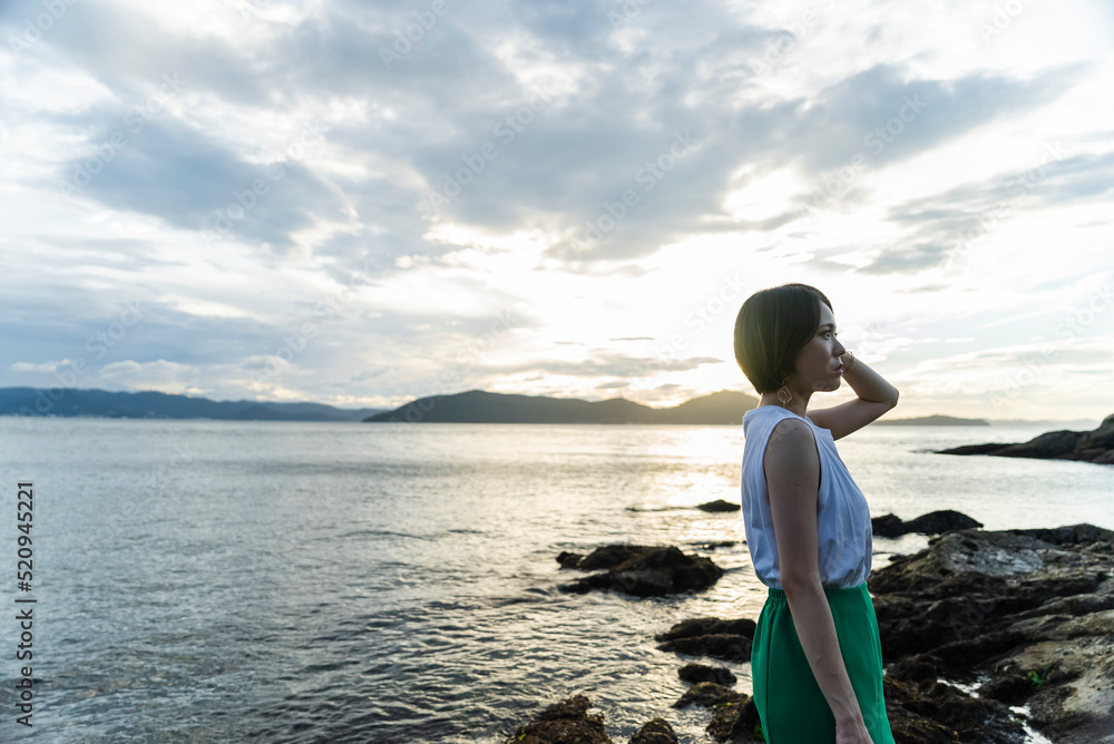 夕暮れの海にいる女性