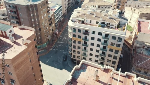 Drone shot of driving cars on junction surrounded by high-rise buildings during summer - Caravaca de La Cruz,Spain photo