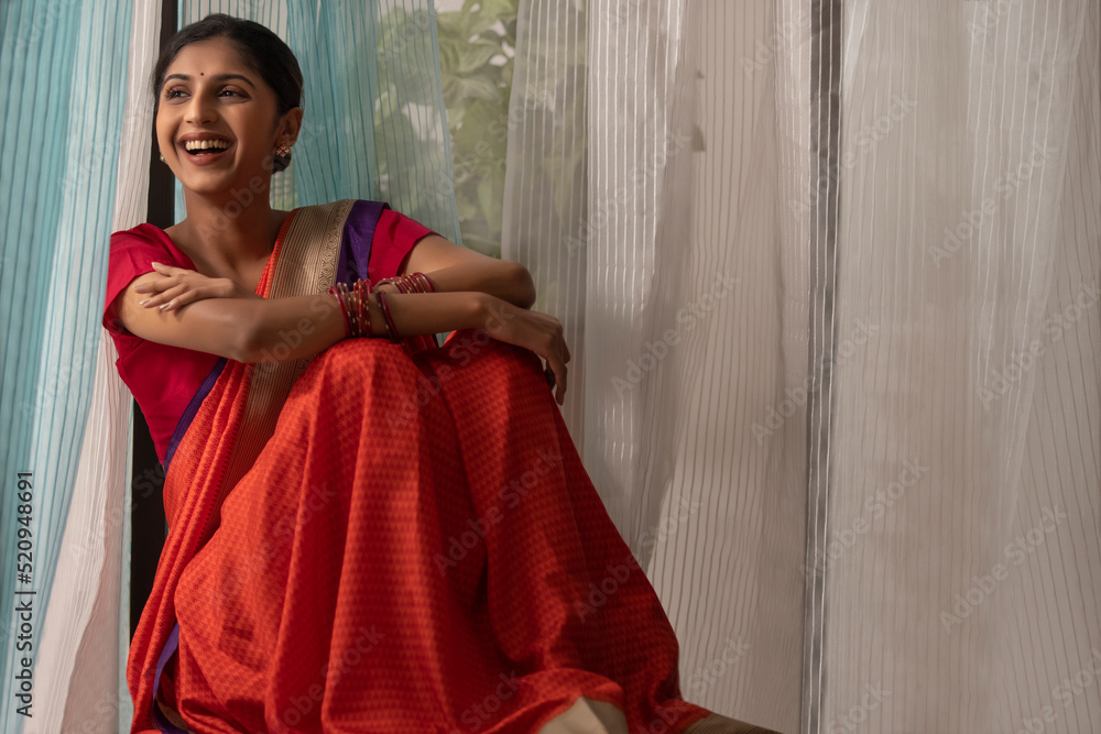 Young woman looking outside while sitting beside window at home Young woman looking outside while sitting beside window at home