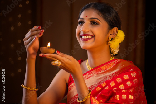 Close-up of a woman in red sari holding diya in her hand on the occasion of Diwali photo