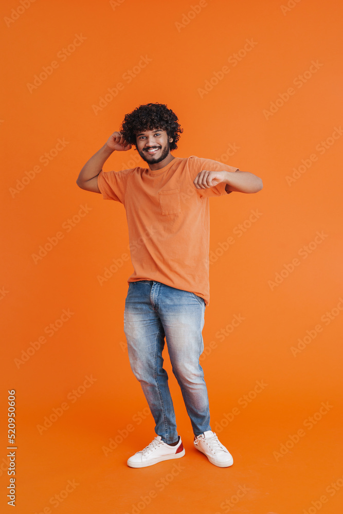 Fototapeta premium Young indian handsome curly smiling man dancing