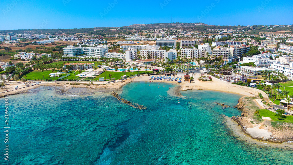 Aerial bird's eye view Pernera beach Protaras, Paralimni, Famagusta, Cyprus. The tourist attraction golden sand bay with sunbeds, water sports, hotels, restaurants, people swimming in sea from above. 
