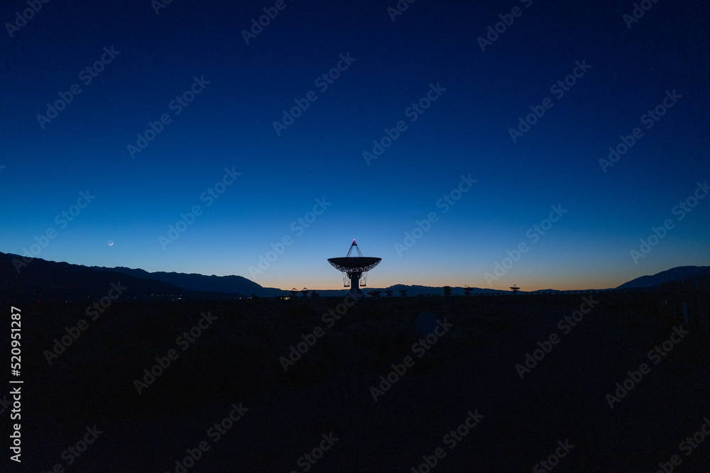 landscape wide shot of Owen Valley Radio Observatory under dark sky and crescent moon
