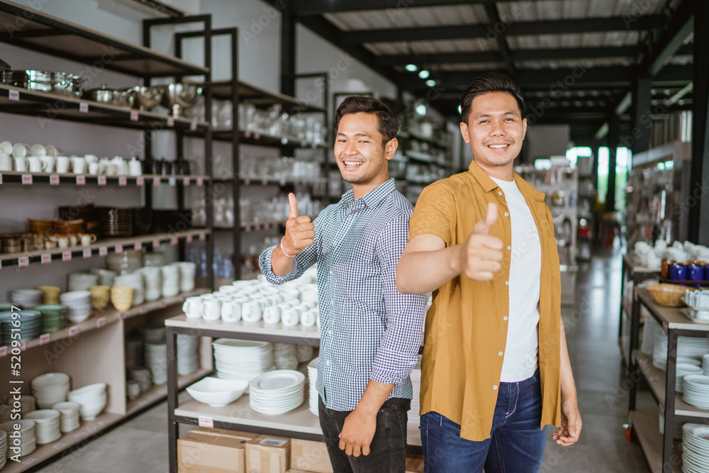 Handsome asian man smiling standing with thumbs up in houseware store