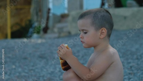 Little Boy Eating A Bun On The Beach