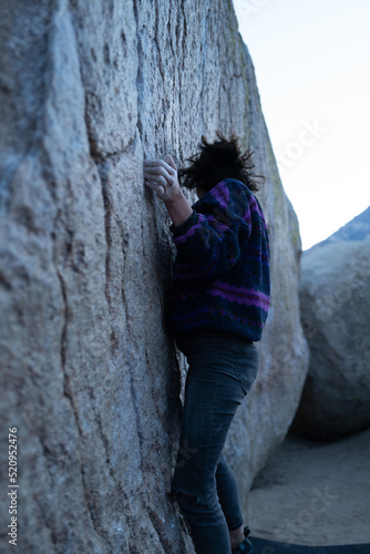 Rock climber starts to climb large boulder